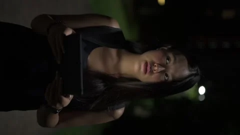 Young woman using digital tablet computer outdoors at night while thinking Stock Footage 317368874