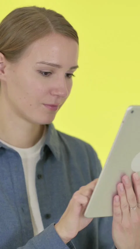 Young Woman using Digital Tablet on Yellow Background, Vertical Video Stock Footage 340039515