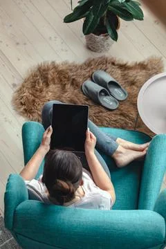 Young woman using digital tablet while sitting in a comfortable Stock Photos