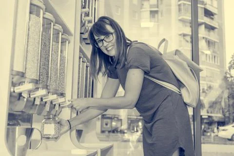 Young woman using dosing container for bulk shopping. Stock Photos