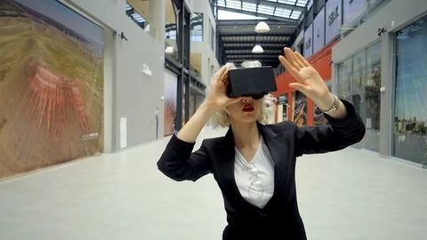 Young woman is using a head-mounted display for entertainment in a modern mall Stock-Footage 86575039