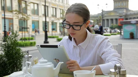 Young Woman Using Her Digital Tablet  and Drinking Tea At A Sidewalk Cafe Vidéo 53199841