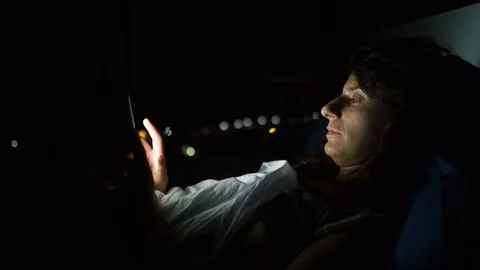 A young woman using her mobile phone or smartphone in her bed by night Stock Footage 116532746