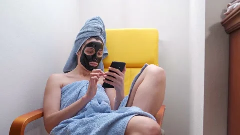 Young woman using her mobile phone with a black facial mask. Stock Footage 145483623