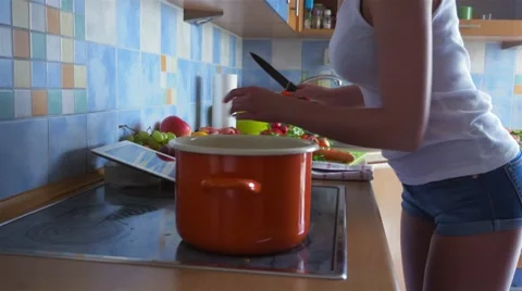 Young woman using her tablet and cooking a dinner Stock Footage 67502633