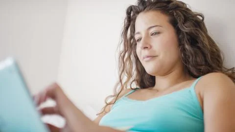 Young woman using her tablet device in bed Stock Photos