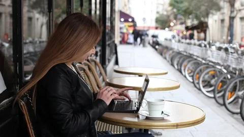 Young woman using laptop computer in street cafe to check email Stock Footage 98093542