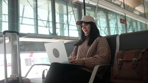 Young woman using laptop computer while waiting for her flight at the airport Stock Footage 334383761