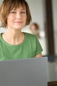 Young woman using laptop computer, looking at the camera Stock Photos