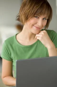 Young woman using laptop computer, smiling for the camera Stock Photos
