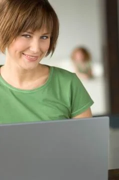 Young woman using laptop computer, smiling for the camera 스톡 사진