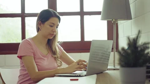 Young woman using laptop sitting at desk in home. Stock Footage 244393389