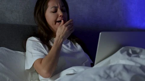 Young woman using laptop while lying in bed at night. Woman working late on.. Stock Footage 295285071