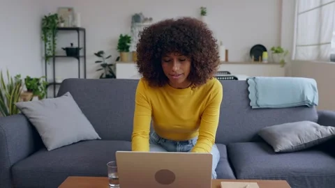 Young woman using laptop while sitting on comfortable sofa, working from home Stock Footage 303472250