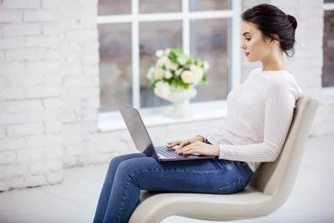 Young woman using laptop while sitting on fancy chair Foto stock