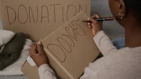Young Woman Using Marker to Write Word Donation in Large Capital Letters on Box Stock Footage 335150364