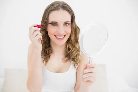 Young woman using mascara while holding a mirror Foto stock