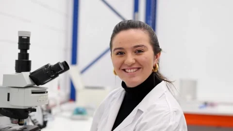 Young woman using microscope and then looking at camera Stock Footage 255196240