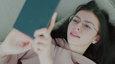 Young woman using mobile device tapping and swiping on tablet lying on sofa Stock Footage 149142721