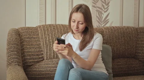 Young woman using mobile phone at home Stock Footage