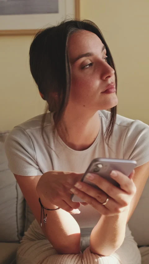 Young woman using mobile phone for texting and scrolling while sitting on sofa Stock Footage 229511569