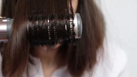 Young woman using a modern rotative hair brush to style her hair. Stockbeeldmateriaal 172361670