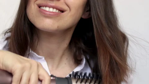 Young woman using a modern rotative hair brush to style her hair Stockbeeldmateriaal 172361741