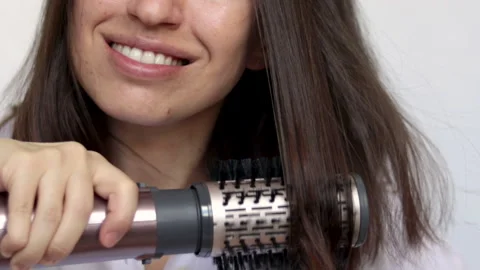 Young woman using a modern rotative hair brush to style her hair Stockbeeldmateriaal 172361916