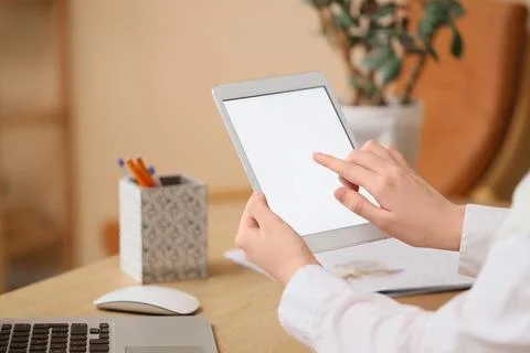 Young woman using modern tablet computer with blank screen at table in room,  Stock Photos