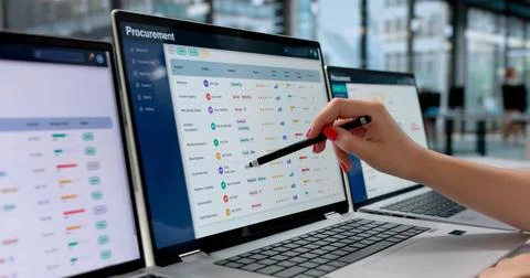 Young Woman Using Multiple Screens To Analyze Supplier Data For Procurement. Stock Photos