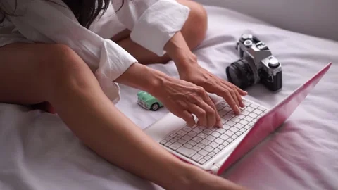 Young woman using a notebook computer while sitting on her bed at home. Stock Footage 195661282