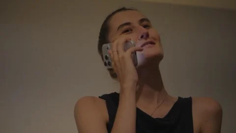 Young woman using or talking on smartphone in a warm bedroom. Video stock 337971617