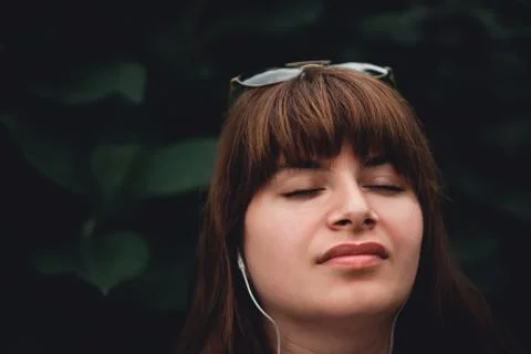 Young woman using phone for listening to music on natural greens background Stock Photos