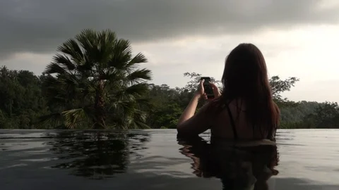 Young woman using a phone in the pool in the jungle in Bali. Stock Footage 104439117