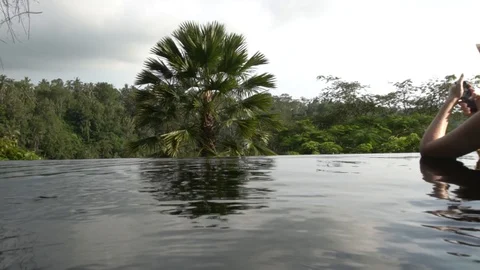 Young woman using a phone in the pool in the jungle of Bali. Stock Footage 104494258