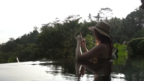 Young woman using a phone in the pool in the jungle. Stock Footage 104494273