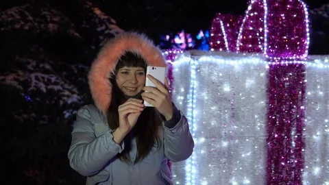 Young woman is using the phone while standing next to a large sparkling gift. Stock Footage 84305975