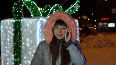 Young woman is using the phone while standing next to a large sparkling gift. Stock Footage 84307220