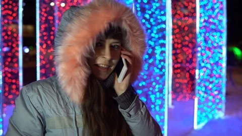Young woman is using the phone while standing next to a large sparkling gift. Stock Footage 84308553