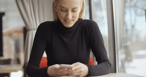 Young woman using phone while waiting for coffee. Stockbeeldmateriaal 102778469