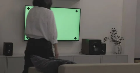 Young woman using the remote control for watching TV on green screen. Stock Footage 149472410