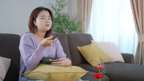 Young woman using remote control select movie streaming platform from television Stock Footage 251013429