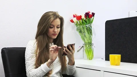 Young woman using smart phone with laptop and colorful stuff on the table in the Stock Footage 73347729