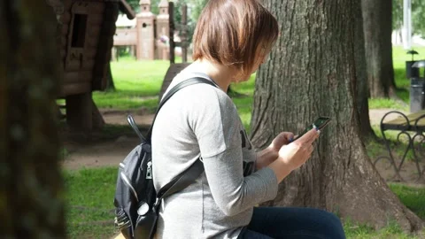 Young woman using smart phone sitting in the park Stock Footage 143274853