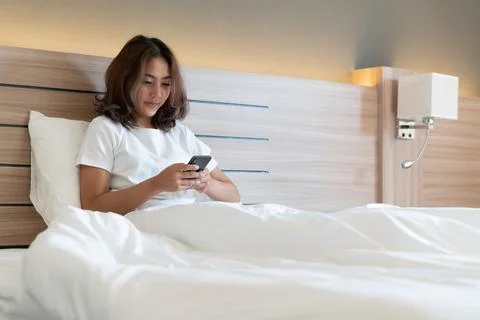 Young woman using smartphone on bed Stock Photos