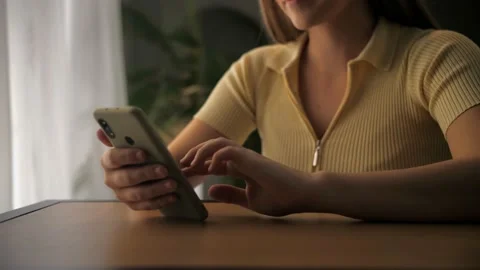 Young woman using smartphone for browsing internet sitting at table in home Stock Footage 209824445