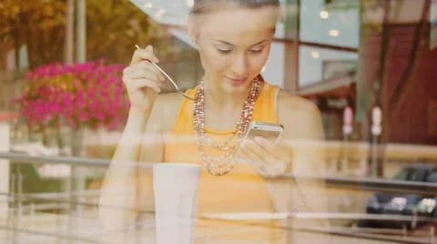 Young Woman using Smartphone in a Cafe, drinking coffee. Slow Motion. Stockbeeldmateriaal 67223537