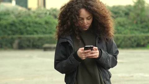 Young Woman using smartphone, communicating, texting, while on a walk. Video stock 75545331