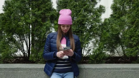 A young woman using smartphone by evergreen thujas. Stock Footage 273015347