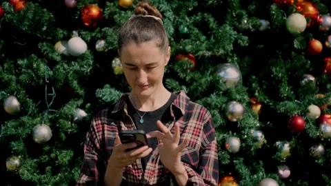 Young woman using smartphone in front of decorated Christmas tree... Vidéo 323733079